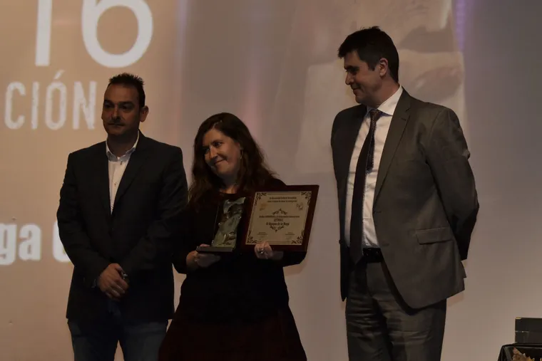 Galardonada mostrando su placa junto a los presentadores de la gala