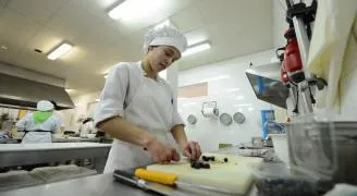 Una alumna de la Escuela de Hostelería del IES Valle de Aller corta alimentos en una cocina profesional