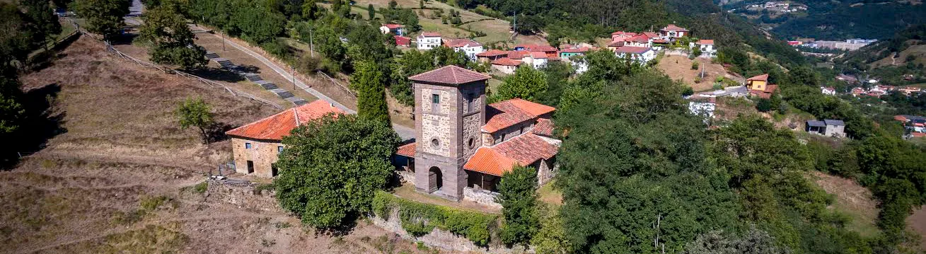 Vista aérea de Cenera con su iglesia entre prados y bosques, en el valle del Caudal